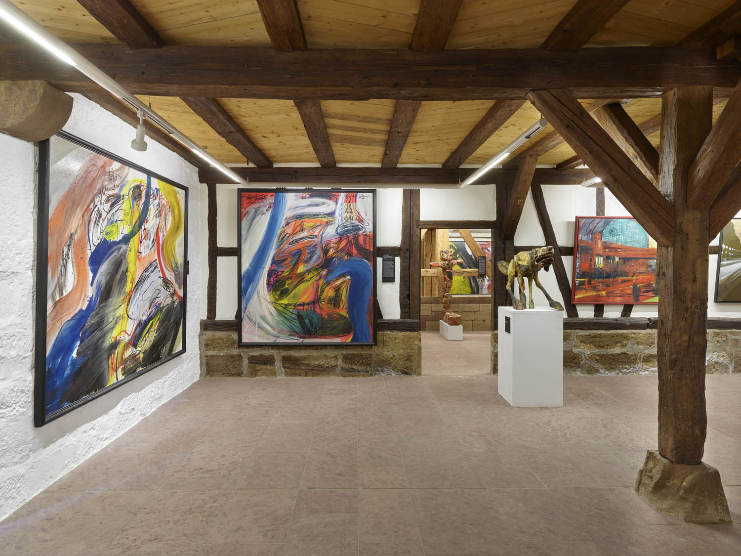 Blick in die Kunstsammlung mit großen, bunten Bildern Fachwerk und Sandsteinboden