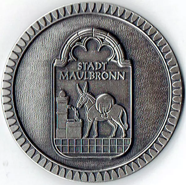 Silberfarbene Medaille, auf der ein Esel am Brunnen zu sehen ist