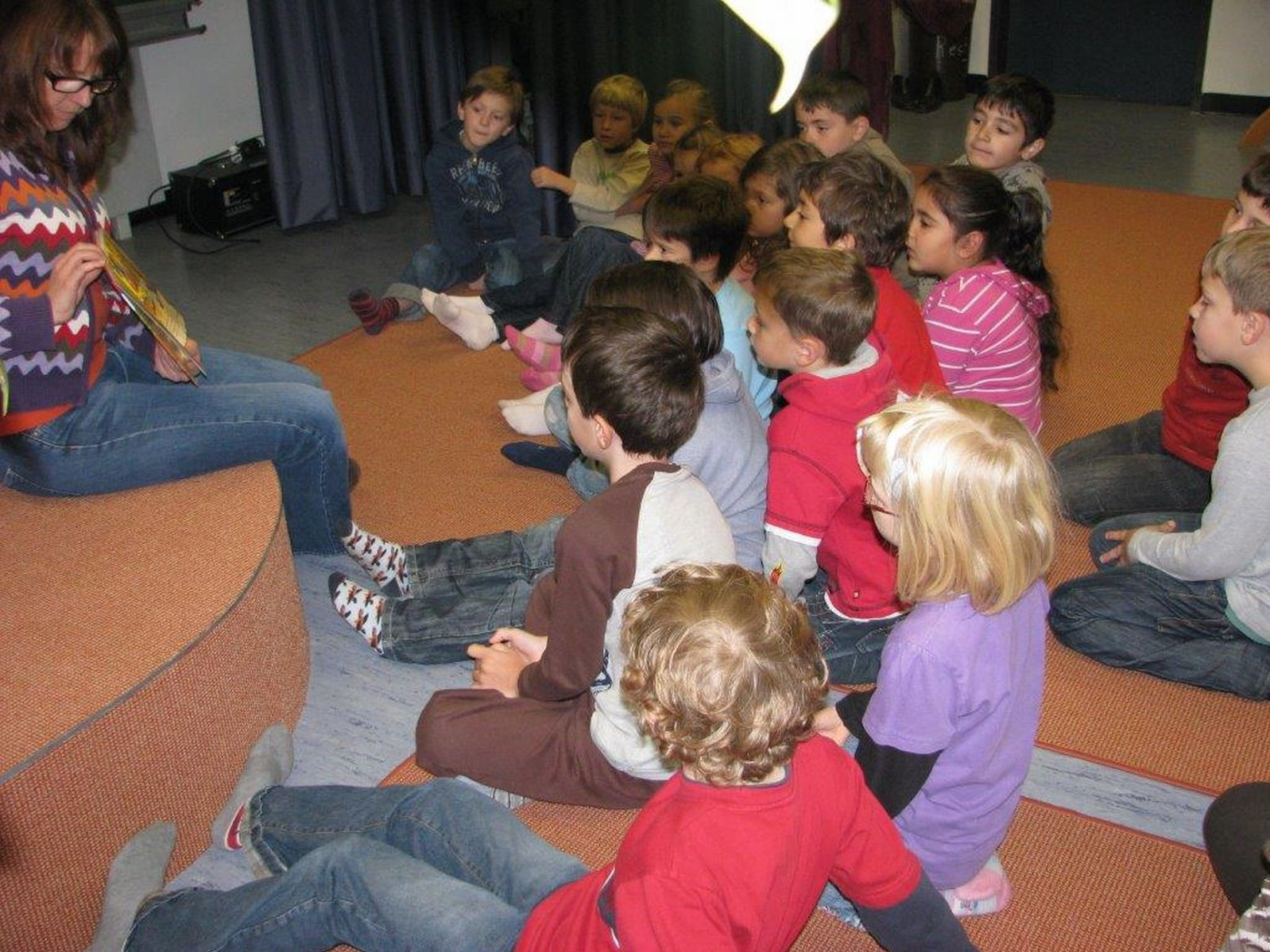 Kinder hören gespannt der Vorleserin zu