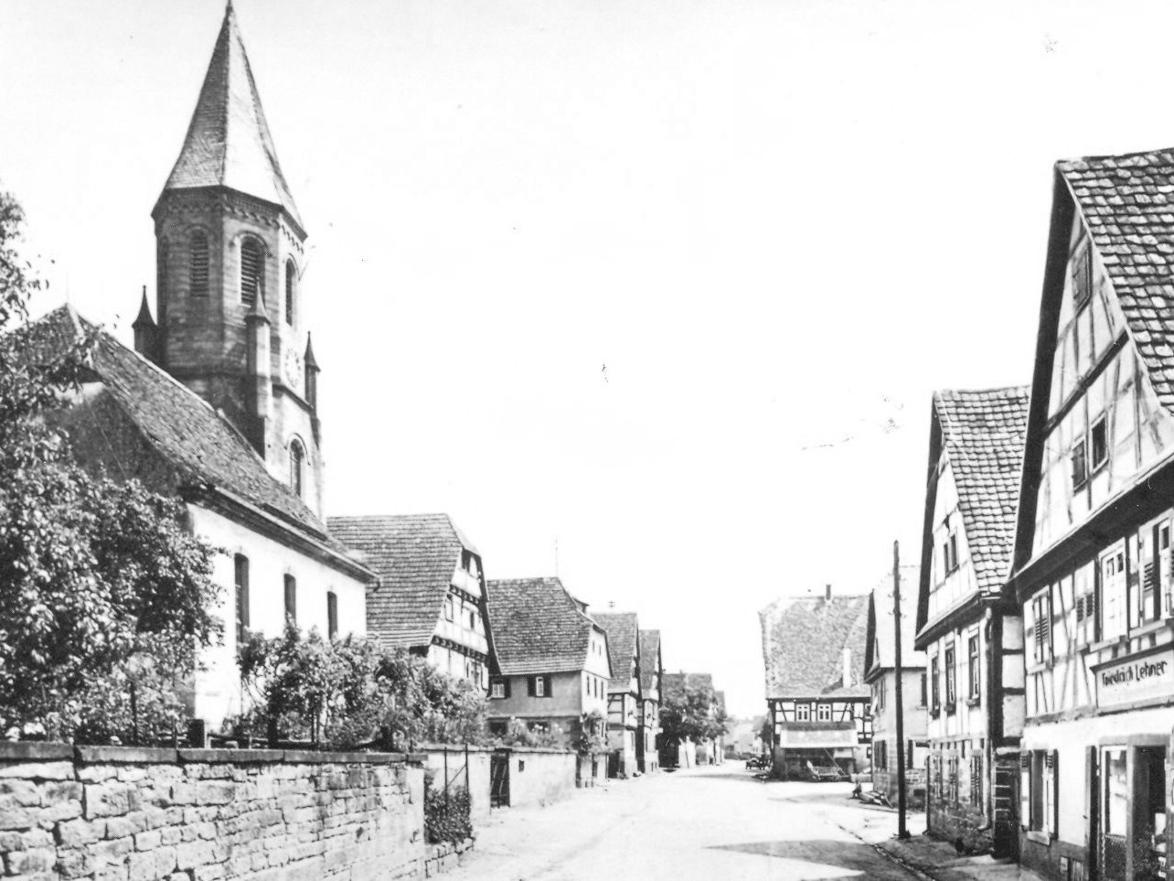 Schwarz-weiß Foto einer Straße gesäumt von Kirche und Fachwerkhäusern