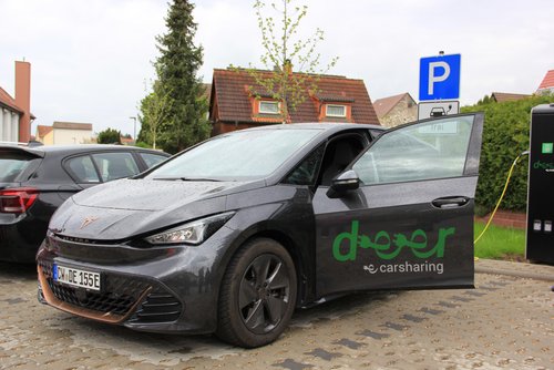 Ein schwarzes Elektroauto mit grüner Aufschrift "deer" auf einem Parkplatz